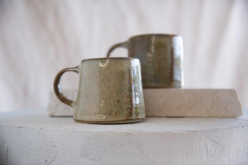 Earthy Tone Ceramic Mugs A stack of mugs in various earthy tones like sage green, sand, and terracotta