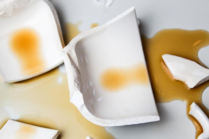 Broken ceramic mug spilling hot coffee after thermal shock failure