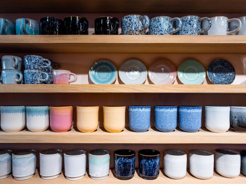 Sustainable Ceramic Mugs Durable ceramic mugs displayed on shelves in a ceramics workshop.