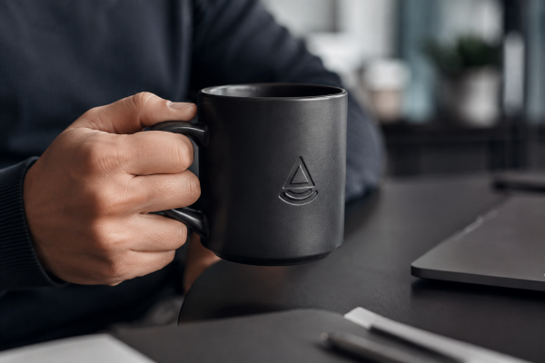 Translating Mug Features to Brand Value A person holding a heavy, matte-black branded mug, conveying a sense of quality and style.